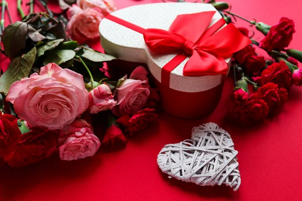 Hermosa tarjeta de felicitación del día de San Valentín. Corazón decorativo, caja de regalo en forma de corazón y flores sobre fondo rojo de cerca —  Fotos de Stock