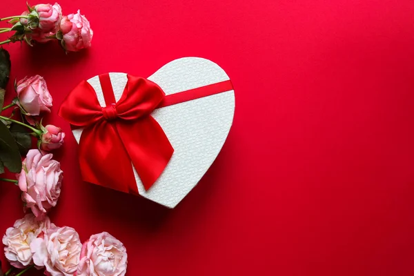 Caja de regalo en forma de corazón y rosas flores sobre fondo rojo con espacio para copiar. Concepto de San Valentín. Vista superior, plano —  Fotos de Stock