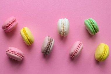 Pastel pembe arka planda Fransız rengarenk badem kurabiyeleri. Seçici odaklanma, üst görünüm, düz yatış