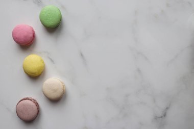 Fotokopi alanı olan mermer bir arka planda Fransız renkli kurabiyeler. Üst manzara, düz uzanma.