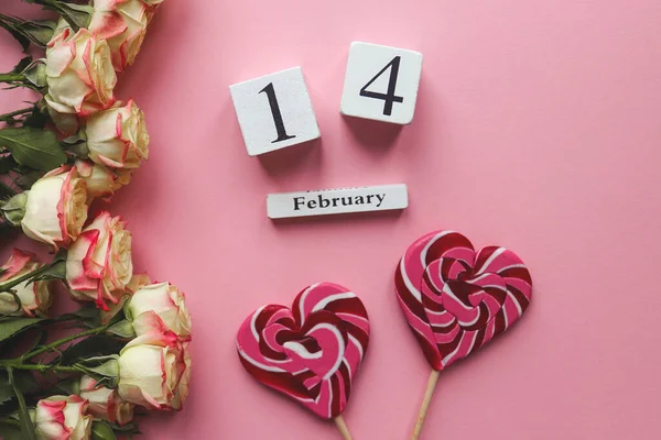 Biglietto d'auguri per San Valentino. Calendario in legno 14 febbraio, bellissimi fiori e caramelle a forma di cuore su sfondo di marmo. Vista dall'alto, disposizione piatta, messa a fuoco selettiva — Foto Stock