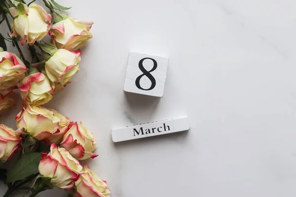 Παγκόσμια Ημέρα της Γυναίκας ευχετήρια κάρτα. Ξύλινο ημερολόγιο 08 Μαρτίου και όμορφα λουλούδια σε μαρμάρινο φόντο με χώρο αντιγραφής. Πάνω άποψη, επίπεδη lay, επιλεκτική εστίαση — Φωτογραφία Αρχείου