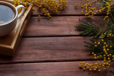 Mimoza çiçekleri ve ahşap tepside bir fincan kahveyle taşralı bahar arkaplanı. Üst görünüm, düz görünüm, kopyalama alanı, seçici odak