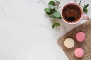 Sıcak mermer masa. Okaliptüs yaprakları, bir fincan kahve ve Fransız pastası. Üst manzara, düz yatış. Doğal stil.