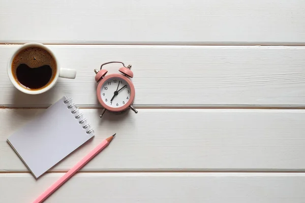 ノートパッド 目覚まし時計 コピースペースのある木製のテーブルの上にコーヒーと鉛筆のカップでビジネスフラットレイ 仕事と朝の時間の開始の概念 — ストック写真