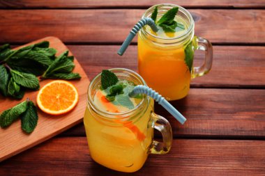 Yaz serinletici içecekler. Kavanozda limonata, buz, nane ve portakalla yakın plan bir masa..