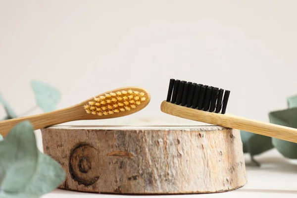 Sepasang sikat gigi bambu ramah lingkungan pada potongan kayu close-up. Kebersihan mulut dan konsep limbah nol. Fokus selektif — Stok Foto