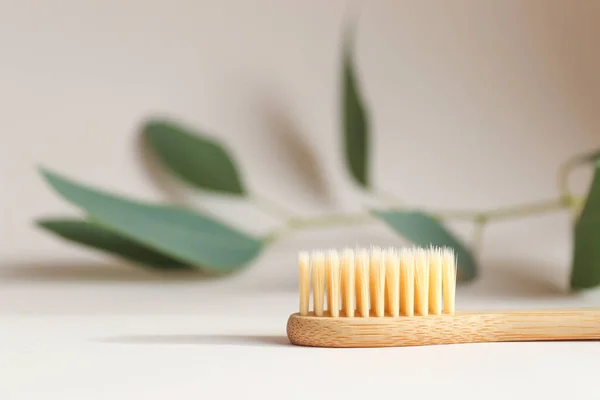 Eco-friendly bamboo toothbrush on a light beige background close-up. Oral hygiene and zero waste concept. Selective focus — Stock Photo, Image
