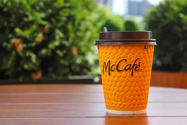 Ukrayna, Kyiv - 4 Haziran 2021: McDonalds 'dan sarı bardak kahve. Masada McCafe 'den gelen bir fincan kahve ve bulanık yapraklara karşı fotokopi alanı. McDonalds restoranında menü.