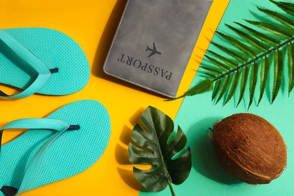 Tatil konsepti. Yaz kompozisyonu. Hindistan cevizi, canavar ve palmiye yaprakları, pasaport ve parlak sarı ve turkuaz arka planda parmak arası terlikler. Üst manzara, düz uzanma