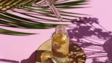 Bir şişe kozmetik yağı ve yakın planda kesilen bir odun damlası. Serum yağı damlalardan damlıyor. Derin gölgeli sert bir ışık. Serum cilt bakımı ürünü
