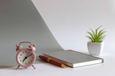 Çalar saati, defteri, kalemi ve bitkisi olan modern bir iş yeri. Seçici odak, uzayı kopyala. Sabah konsepti.