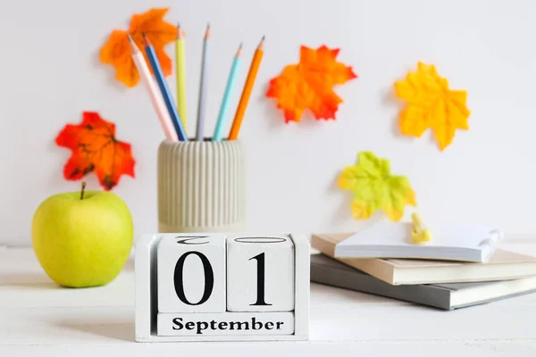 Back to school concept. School stationery, green apple and calendar dated September 1st on the table. Selective focus.