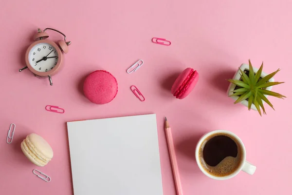 ノートパッド 目覚まし時計 ピンクの背景にコーヒーとマカロンのカップを持つ職場 ビジネス フリーランス 教育の概念 トップビュー フラットレイアウト — ストック写真