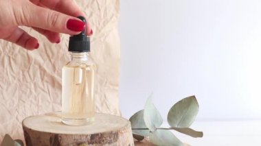 Dişi el, elzem yağdan bir damla alır ve yağ damlatır. Bir şişe kozmetik yağı ve ahşap kaplamalı damlalar. Serum cilt bakımı ürünü. Seçici odak
