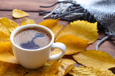 Sıcak sonbahar kompozisyonu, bir fincan kahve, sıcak ekose ve sarı sonbahar yaprakları. Yakın çekim, seçici odaklanma