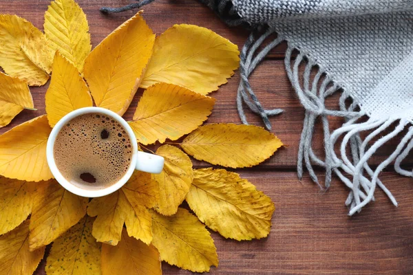 Cozy autumn flat lay with cup of coffee, warm plaid and yellow autumn leaves. Top view