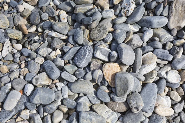 Pietre di mare o la pietra nera liscia umida sulla spiaggia come sfondo — Foto Stock