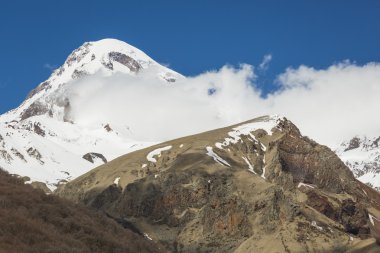 Kazbek peak mountains and blue sky. Georgia. clipart
