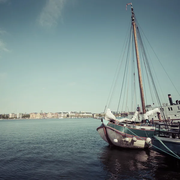 Old city buildings and old boats on water under blue sky in Stoc — Stock Photo, Image