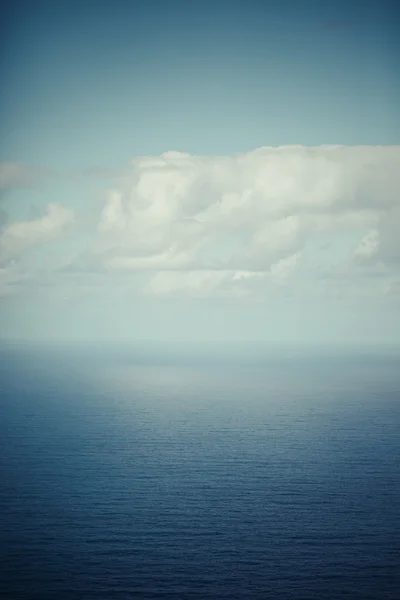 Vita fluffiga moln blå himlen över en ytbehandla av havet — Stockfoto