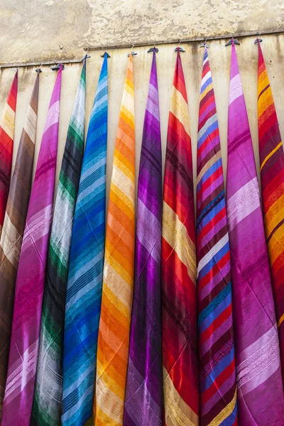 Colorful fabrics and carpets for sale on a street in Medina of E — Stock Photo, Image