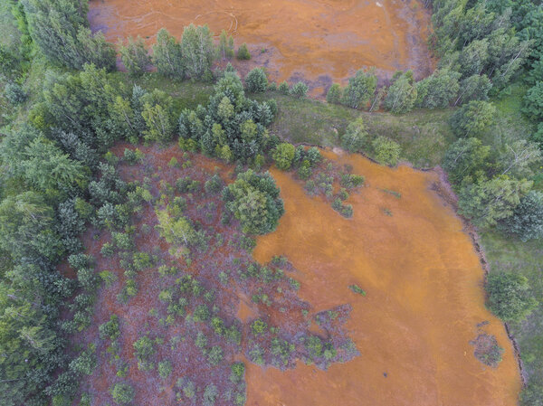 Old sulfuric acid natural tank orange color in south of Poland.