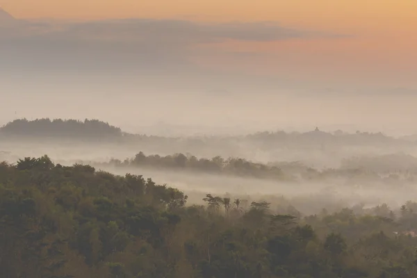 Kleurrijke zonsopgang boven Merapi vulkaan en Borobudur tempel in mis — Stockfoto