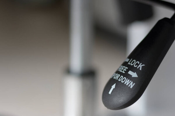 Closeup of black lever adjustable for lifting office chair mechanism.