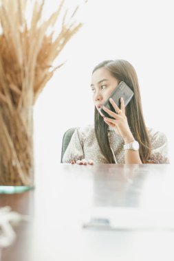 Doğal beyaz arka planı olan bir masada çalışan genç ve güzel bir kadın..