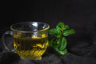 Doğal koyu arka planda izole edilmiş cam fincanda sıcak çay..