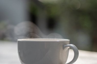 White coffee cup on natural blurred background.