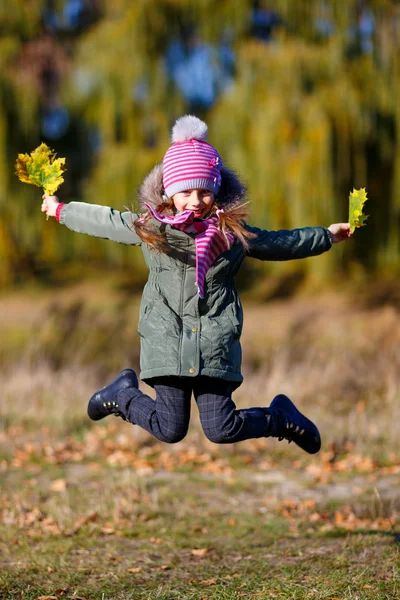 Menina jamping com folhas de outono — Fotografia de Stock