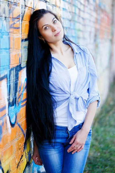 Beautiful young girl near a wall with graffiti. — Stock Photo, Image