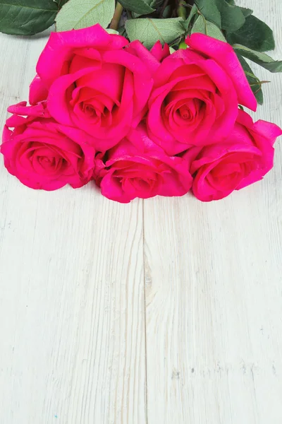 Μάτσο τριαντάφυλλο σε λευκή ξύλινη επιφάνεια — Φωτογραφία Αρχείου