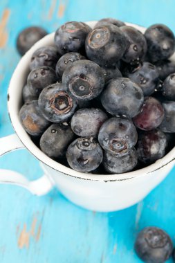 ahşap masa üzerinde bir fincan taze yaban mersini