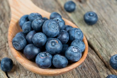 ahşap masa üzerinde bir tahta kaşık içinde taze yaban mersini