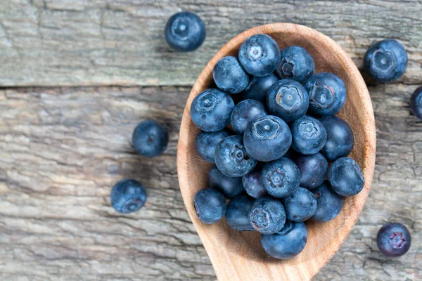 Fresh blueberries in a wooden spoon over wooden table — Stock Photo, Image