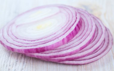 Beyaz ahşap yüzey üzerinde kırmızı soğan dilimleri