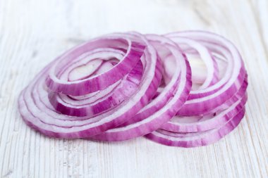 Beyaz ahşap yüzey üzerinde kırmızı soğan dilimleri