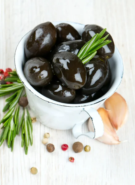 Olive nere in una tazza metallica su una superficie di legno — Foto Stock