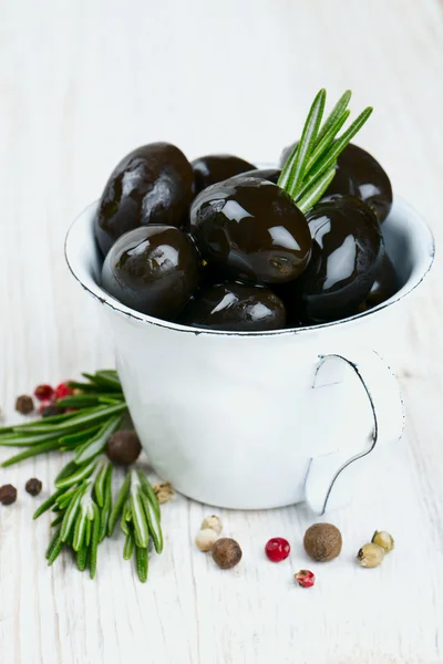 Svarta oliver i en metall kopp på träytan — Stockfoto