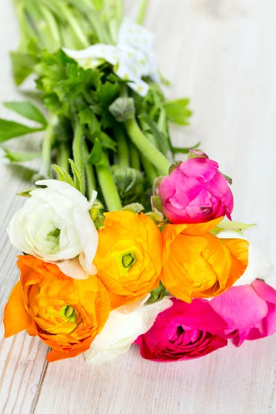 Buquê de branco, rosa e laranja buttercups na mesa de madeira — Fotografia de Stock