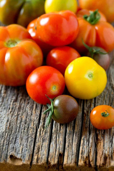 Colorful organic tomatoes on wooden surface — Stock Photo, Image