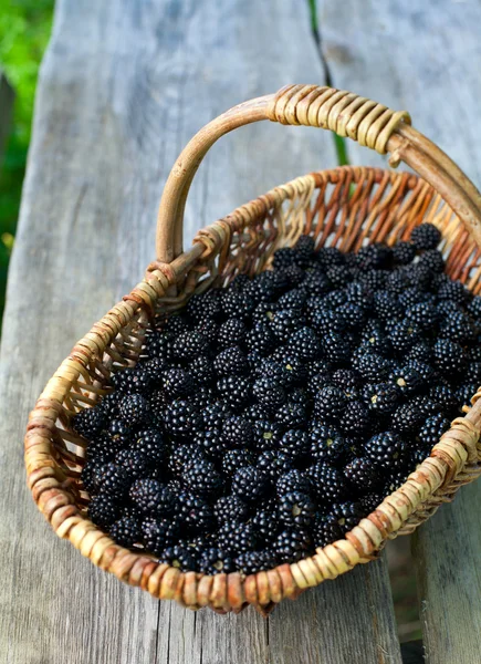 Blackberries in basket on wooden surface — Stock Photo, Image