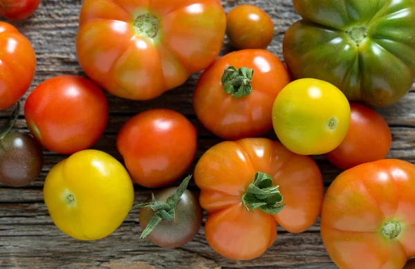 Kleurrijke biologische tomaten op een houten oppervlak — Stockfoto