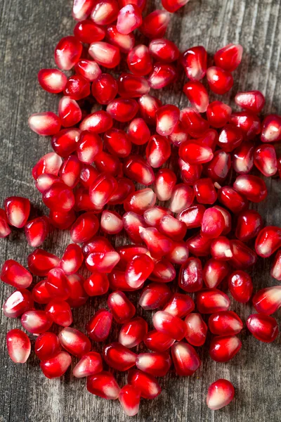 Pomegranate seeds on wooden surface — Stock Photo, Image