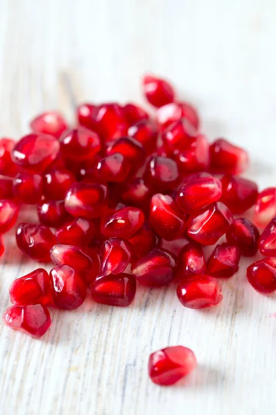 Pomegranate seeds on wooden surface — Stock Photo, Image