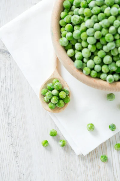 Guisantes congelados en la superficie de madera — Foto de Stock