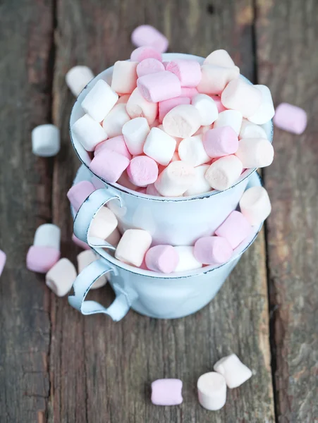 Marshmallows em copos metálicos em mesa de madeira — Fotografia de Stock